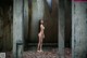 A naked woman standing in an abandoned building.