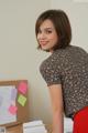 A woman standing in front of a desk with papers on it.