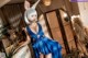 A woman in a blue dress and bunny ears posing for a picture.