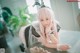 A woman with pink hair and bunny ears sitting at a table.