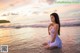 A woman in a white dress sitting in the water.