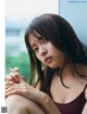 A woman sitting on a window sill in front of a window.