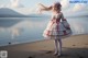 A woman in a pink and white dress standing on a beach.