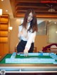 A woman in a white shirt and black skirt playing a game of mahjong.