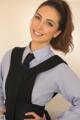 A woman in a blue shirt and black vest posing for a picture.