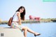 A woman sitting on the edge of a concrete wall by the water.